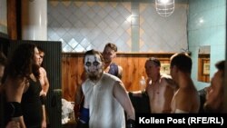 Кечистът Скела гледа към обектива. Той е заобиколен от колеги, които са в съблекалнята на залата, в която се бият.