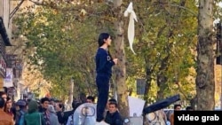 Протест девушки без платка, стоящей по улице Энгелаб в Тегеране, против исламского дресс-кода в Иране. Иллюстративное фото.
