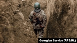 Mai mulți luptători georgieni au murit în Ucraina. Imagine cu un soldat georgian în Ucraina. Pe casca acestuia se află steagul Georgiei, pe armă, cel al Ucrainei.