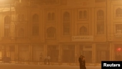 Egy nő sétál az Imam al-Abbas szentély közelében egy homokvihar idején az iraki Kerbala szent városában, 2022. június 26-án.