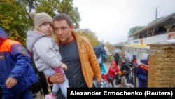 Цивилите евакуирани од градот Керсон, кој е под руска контрола, одат од траект за да се качат во автобус