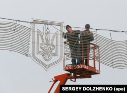 Muncitori instalând decorațiuni cu tridentul ucrainean, Kiev, 2014.