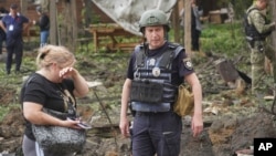 Žena plače dok policajci pregledaju lokaciju ruskog raketnog napada na periferiji Harkiv u Ukrajini u kome je poginulo petoro ljudi, dok je šesnaestoro povređeno, 19. maj 2024. 