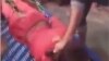 The video shows a man pinning the transgender woman face down on a bed with his foot and beating her bare buttocks with a belt.