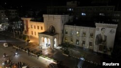 Жители Хамы собираются перед зданием губернаторского дворца, с уже изрешечённым пулями изображением на фасаде президента Сирии Башара аль-Асада, после того как повстанцы захватили город, 5 декабря 2024 г.