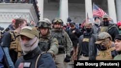 Jessica Marie Watkins (balról a második) and Donovan Ray Crowl (középen) és az Oath Keepers (eskütartók) szélsőjobboldali milícia más tagjai a Capitoliumnál 2021. január 6-án. A 2009-ben alapított milícia döntően a fegyveres szervek egykori tagjai közül próbál toborozni. 