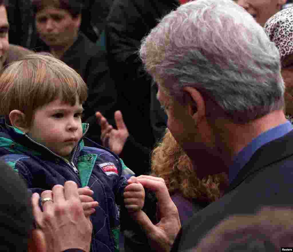Presidenti amerikan Bill Clinton duke përshëndetur një fëmijë nga Kosova, i cili ka ikur nga lufta dhe është strehuar në Gjermani, 6 maj 1999. Foto Reuters. 