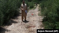 A plainclothes police officer indicates the bloody spot where popular Pakistani blogger and social-media activist Muhammad Bilal Khan was killed in Islamabad on June 16.