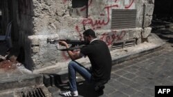 Syria -- A Syrian rebel takes position on a street in the northern city of Aleppo, 03Aug2012