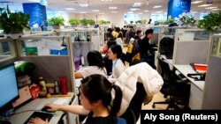 A Ctrip.Com online utazási iroda munkatársai dolgoznak Sanghajban egy, a kormány által újságíróknak szervezett munkahelybejárás közben, 2021. január 14-én.