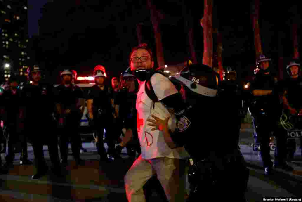  Zyrtarët e zbatimit të ligjit shihen duke mbajtur një burrë gjatë protestës kundër vrasjes së afrikano-amerikanit, Floyd.