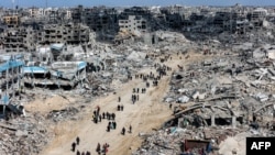 Oamenii trec pe lângă clădirilor prăbușite în tabăra Jabalia pentru refugiații palestinieni din nordul Fâșiei Gaza. 19 ianuarie 2025, după intrarea în vigoare a acordului de încetare a focului.