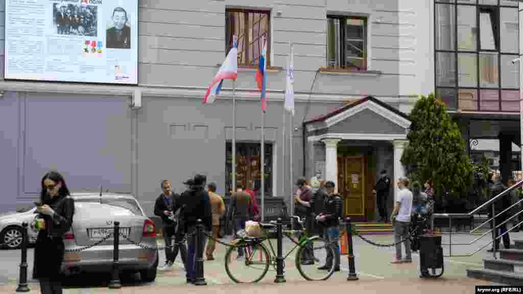 Черга перед відділенням банку &laquo;Росія&raquo; на проспекті Кірова у Сімферополі. Щоб люди не нудьгували, їм транслюють на великому екрані, встановленому на фасаді будівлі, документальний фільм &laquo;Безсмертний полк&raquo;