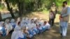A Security official stands guard as school girls attend their school in open air following the school building destruction by suspected militants, in Tirah valley, in Khyber tribal district. (file photo)