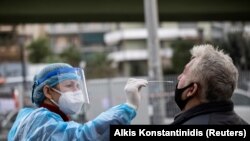 Egy egészségügyi dolgozó mintát vesz egy férfitől az antigén gyorsteszthez egy autós tesztelőponton Athénban, Görögországban, 2020. december 18-án. 