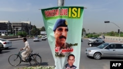 FILE: A cyclist rides past a banner bearing the image of former Inter-Services Intelligence (ISI) Chief Lt. General Zaheerul Islam in Islamabad, April 2014.