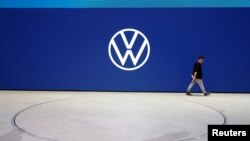 An employee of Volkswagen AG walks past the revised logo 