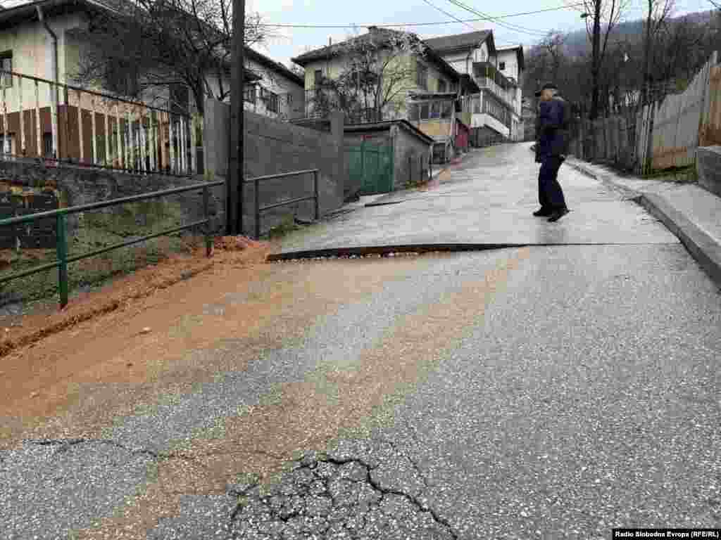 Policajac posmatra pukotine na asvaltu u sarajevskom naselju Širokača, koje je uzrokovala obilna kiša.