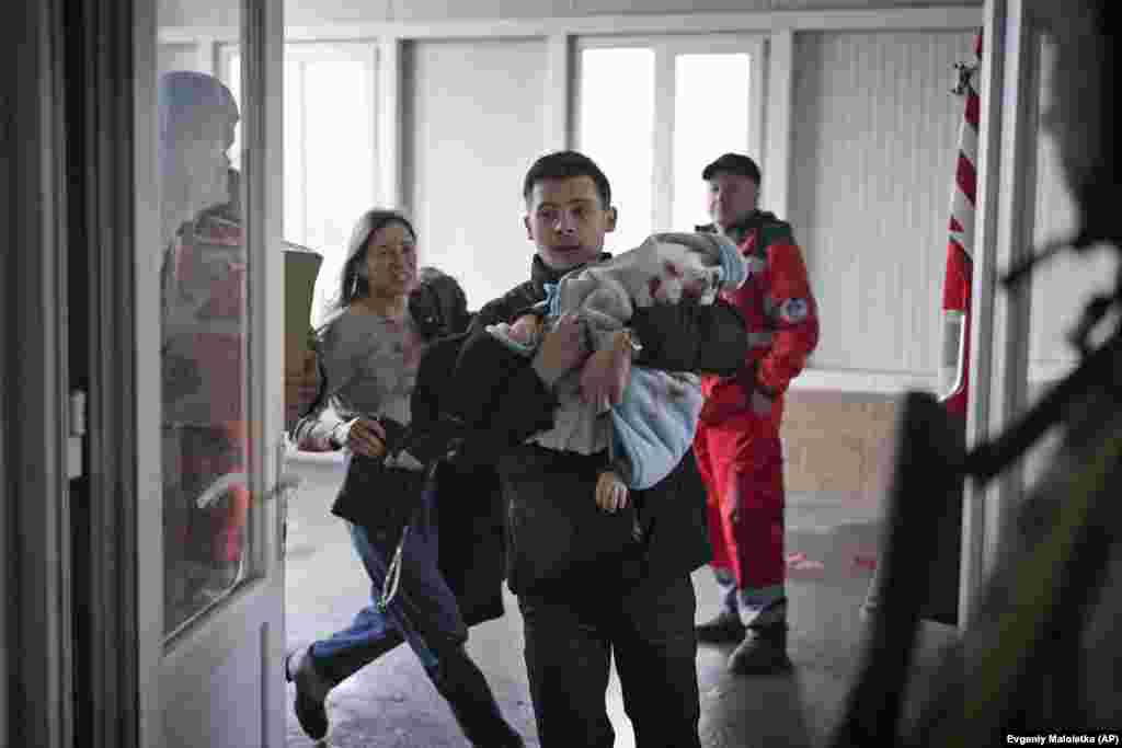 Maryna Yatsko (left) and her boyfriend, Fedir, run into a Mariupol hospital carrying Yatsko's injured 18 month-old son, Kyrylo, on March 4. 