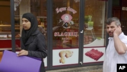 A butcher talks on his mobile phone outside a halal butcher shop in Amsterdam.