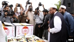 Hafiz Saeed (2-R), head of banned Islamic charity Jamat-ud-Dawa that now works with a new name Falah-e-Insaniyat Foundation, dispatch relief goods and cash funds for the victims of earthquake, at their relief good collection center in Islamabad on November 2.