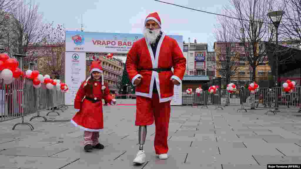 Një vajzë e vogël dhe një burrë "me këmbë protetike të veshur me kostume të kuqe marrin pjesë në edicionin e nëntë të mini-maratonës “Vrapo Babadimër” në Prishtinë, që ka për qëllim mbledhjen e fondeve për çështje humanitare.