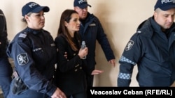 Евгения Гуцул в сопровождении сотрудников полиции