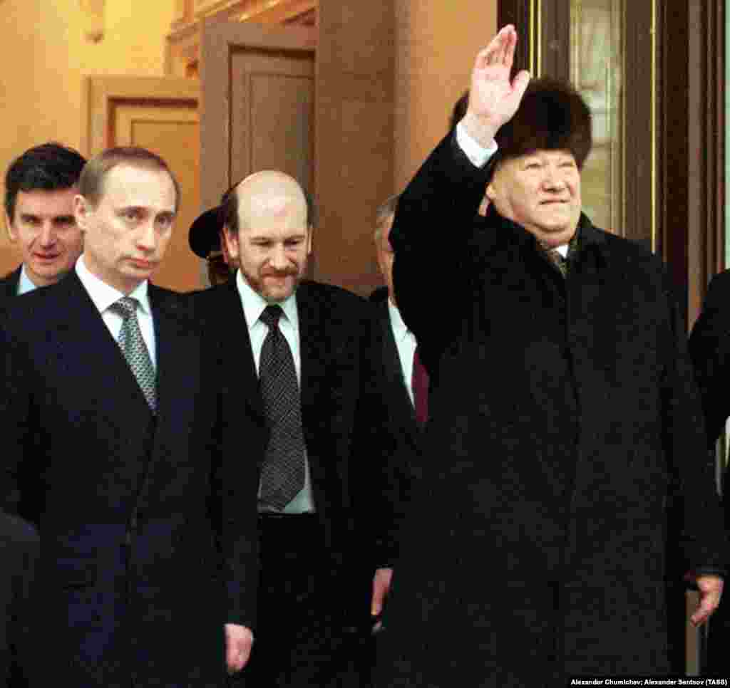 Єльцин махає рукою, стоячи поруч з Володимиром Путіним 31 грудня 1999 року. Того дня Єльцин передав президентське крісло Путіну після майже десятирічного перебування при владі. Єльцин залишив свою посаду, як каже частина фахівців, глибоко непопулярним – здебільшого через економічні труднощі, які загрожували країні під час його президентства. Але інші вважають, що він запобіг потенційній громадянській війні в Росії під час масштабних політичних змін, які він спостерігав після краху Радянського Союзу. Єльцин помер у квітні 2007 року у віці 76 років 